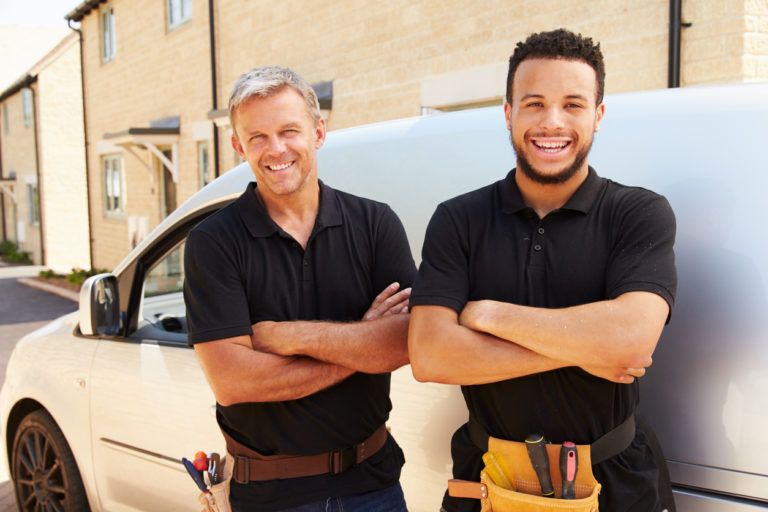 two smiling contractors in front of van